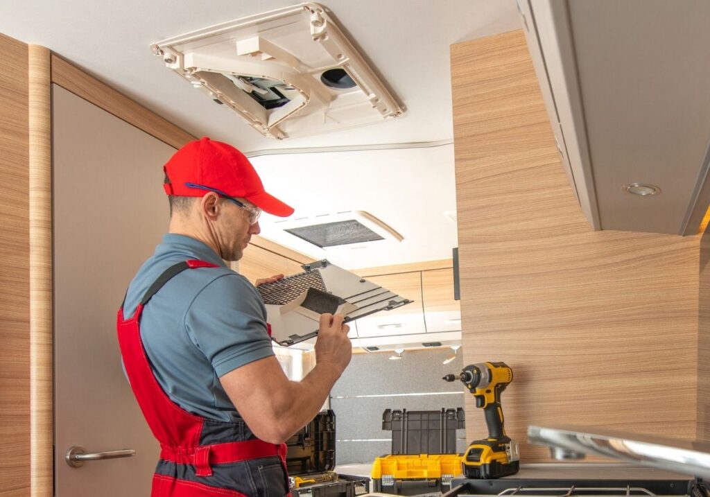 Close-up of RV air conditioning unit with tools laid out for on-site repair