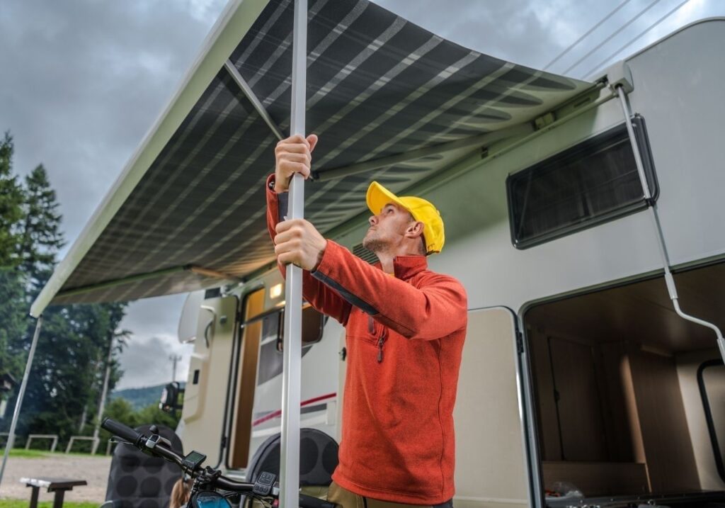 Close-up of damaged RV awning fabric and bent support arm before mobile repair