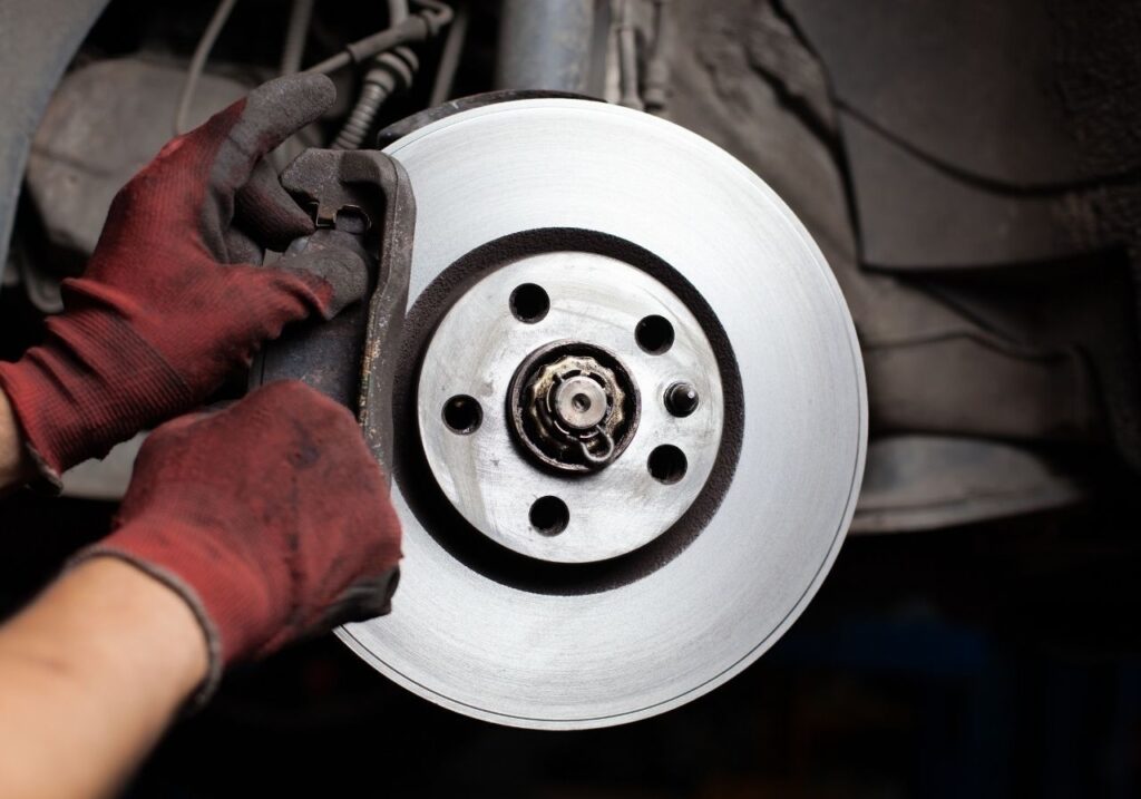 Certified RV technician inspecting suspension under a fifth wheel RV